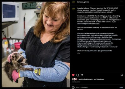 Wildlife rehabber holding baby raccoon while wearing Ironclad gloves and blue kevlar sleeves.